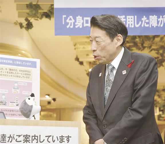 分身ロボット「オリヒメ」(左)を介した接客を体験する福岡県の服部誠太郎知事=2024年12月、福岡市東区のマリンワールド海の中道