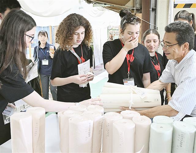 見学ツアーで精練前の生地に触れる人たち=10月、京都府京丹後市