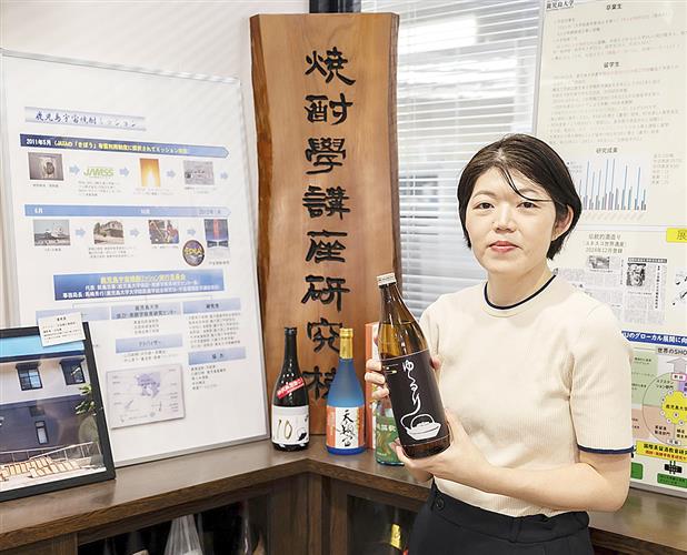 鹿児島大の研究センター内で焼酎を持つ吉崎由美子准教授=鹿児島市
