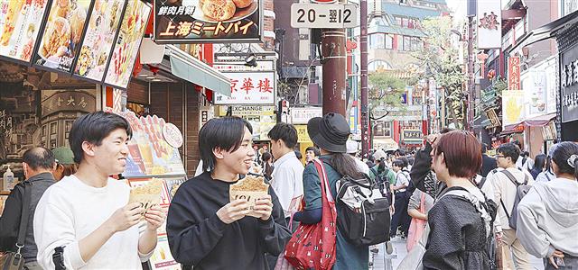 横浜中華街の店先でフライドチキンを食べる男性=10月、横浜市