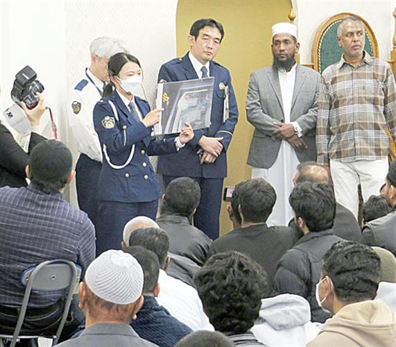 名古屋港モスクを訪れた人たちに、自転車に乗る際のヘルメット着用を呼びかける警察官(中央)=名古屋市(愛知県警提供)