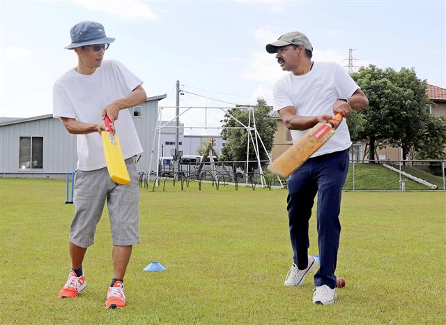クリケットの体験会で参加者を指導するビネイ・クマールさん(中央)=9月、浜松市